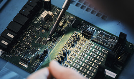 A printed circuit board being repaired by an engineer.