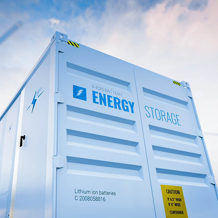 A battery energy storage system among solar panels and wind turbines.